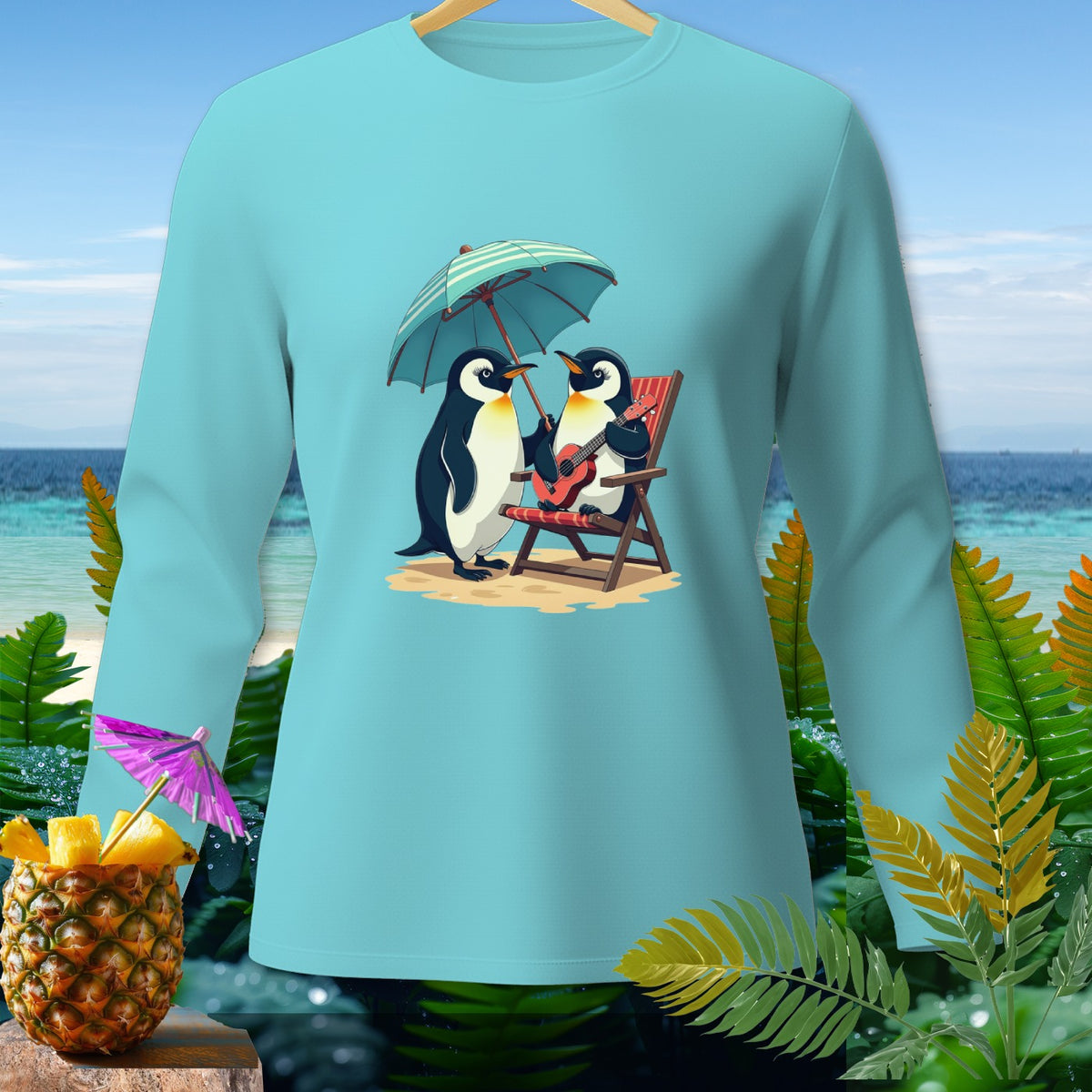 Light blue long-sleeve shirt with two penguins under an umbrella on a beach.