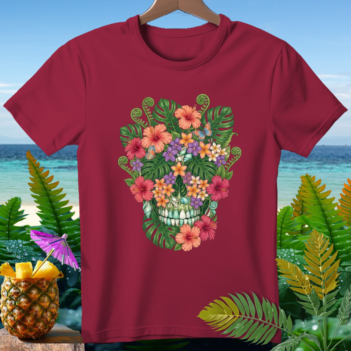 Burgundy t-shirt with a floral skull design, set against a tropical beach background.