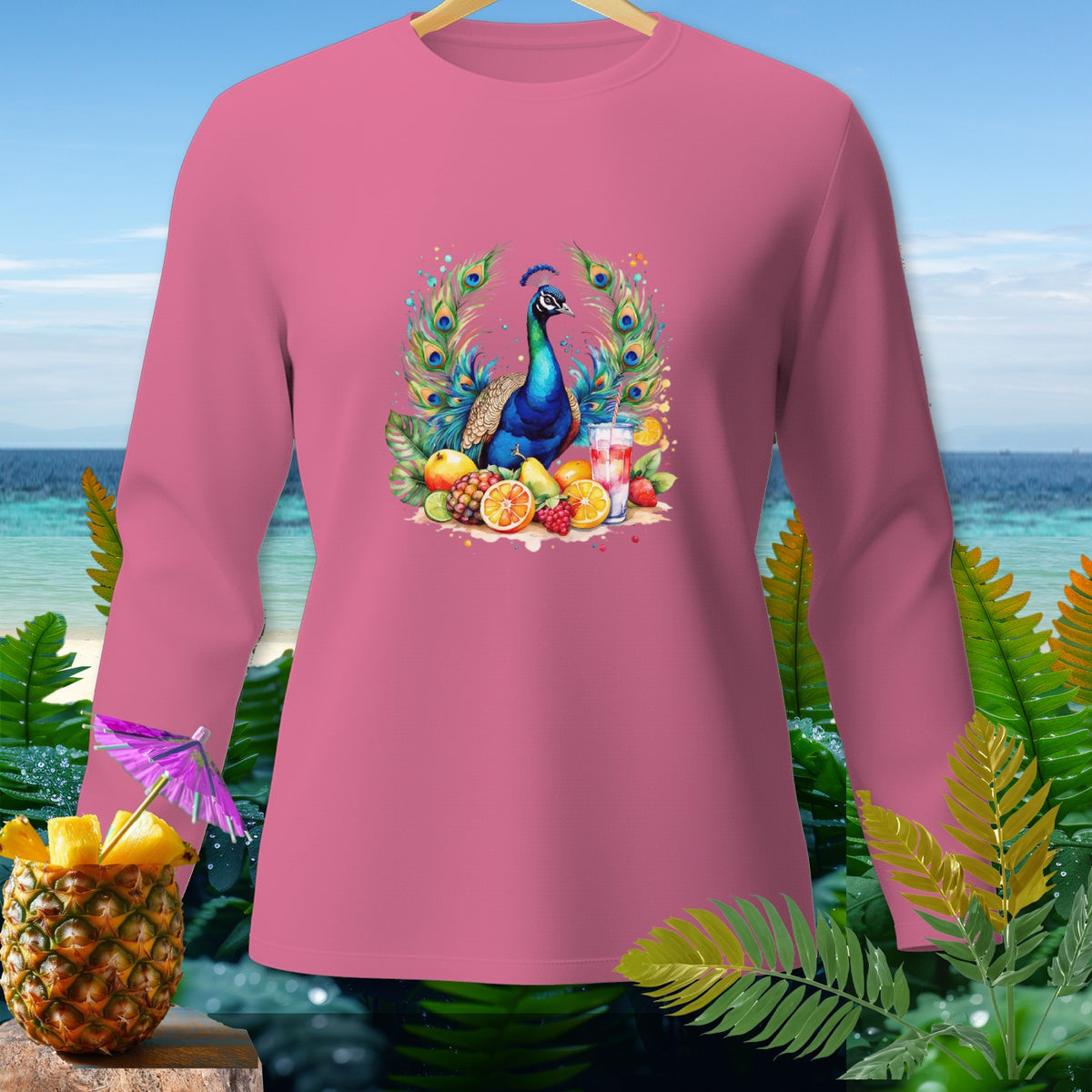 Pink long-sleeve shirt with peacock and fruit graphic, against a tropical beach backdrop.