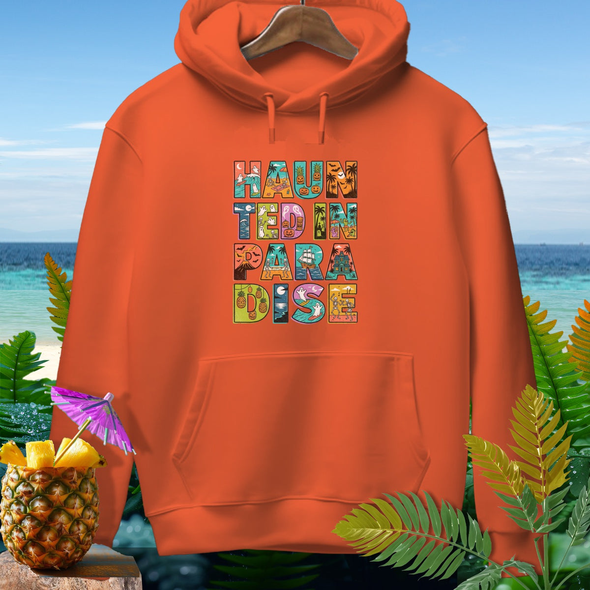 Orange hoodie with "Haunted In Paradise" text in colorful, themed blocks.