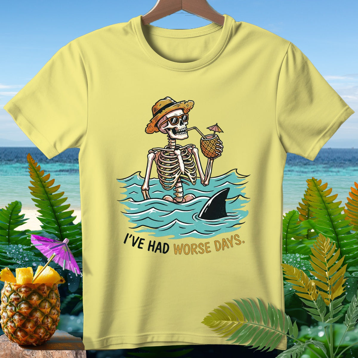 Skeleton in water with a pineapple drink, shark fin, and text "I'VE HAD WORSE DAYS."