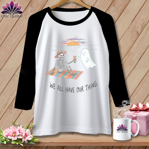 T-shirt with skeleton and ghost on beach, text "WE ALL HAVE OUR THING."