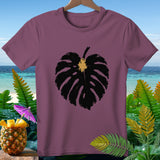 Plum t-shirt with a black monstera leaf graphic and tropical background.