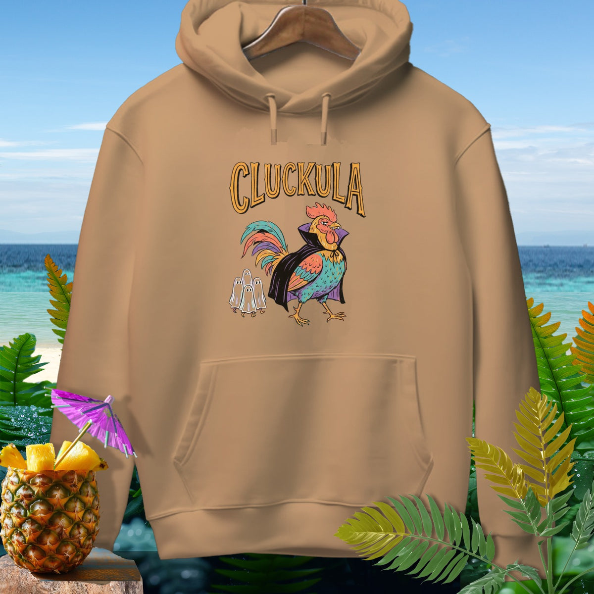 Beige hooded sweatshirt featuring a graphic of a colorful rooster vampire and ghost figures under the text CLUCKULA.