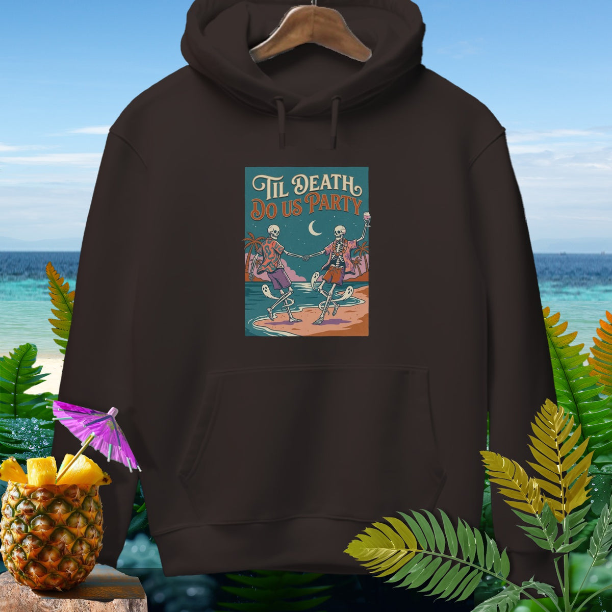 Dark brown hoodie with "Til Death Do Us Party" graphic of dancing skeletons on a beach.