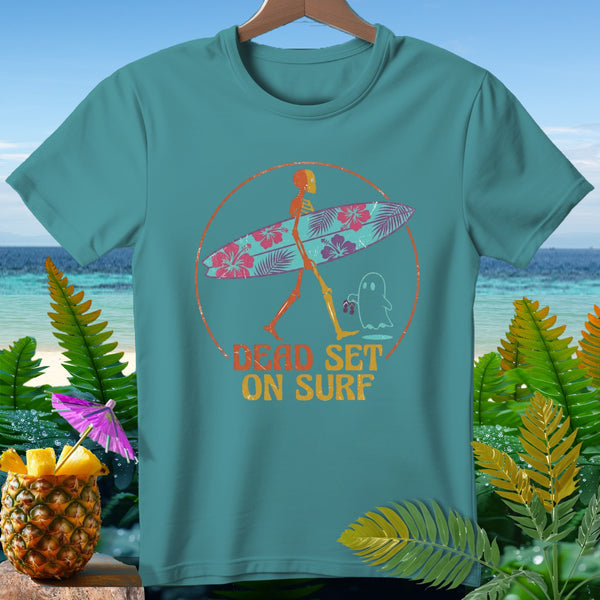Teal t-shirt with skeleton carrying surfboard, text "DEAD SET ON SURF", and a ghost.