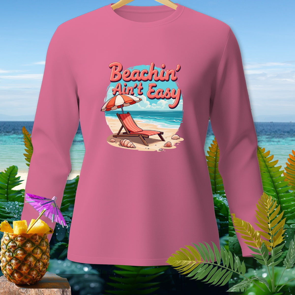Pink long-sleeve shirt with "Beachin' Ain't Easy" graphic and beach scene.