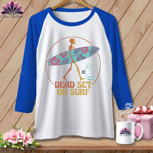 Raglan t-shirt with skeleton holding a surfboard and "DEAD SET ON SURF" text.