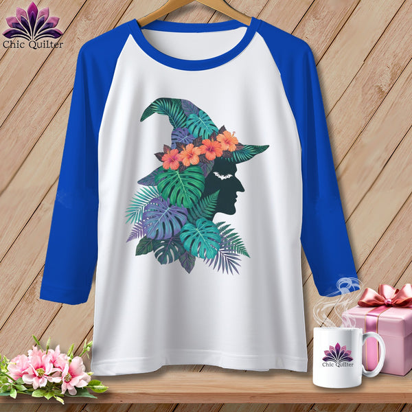 White baseball tee with witch silhouette adorned with tropical leaves and flowers.