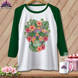White baseball tee with a floral skull graphic and green sleeves.