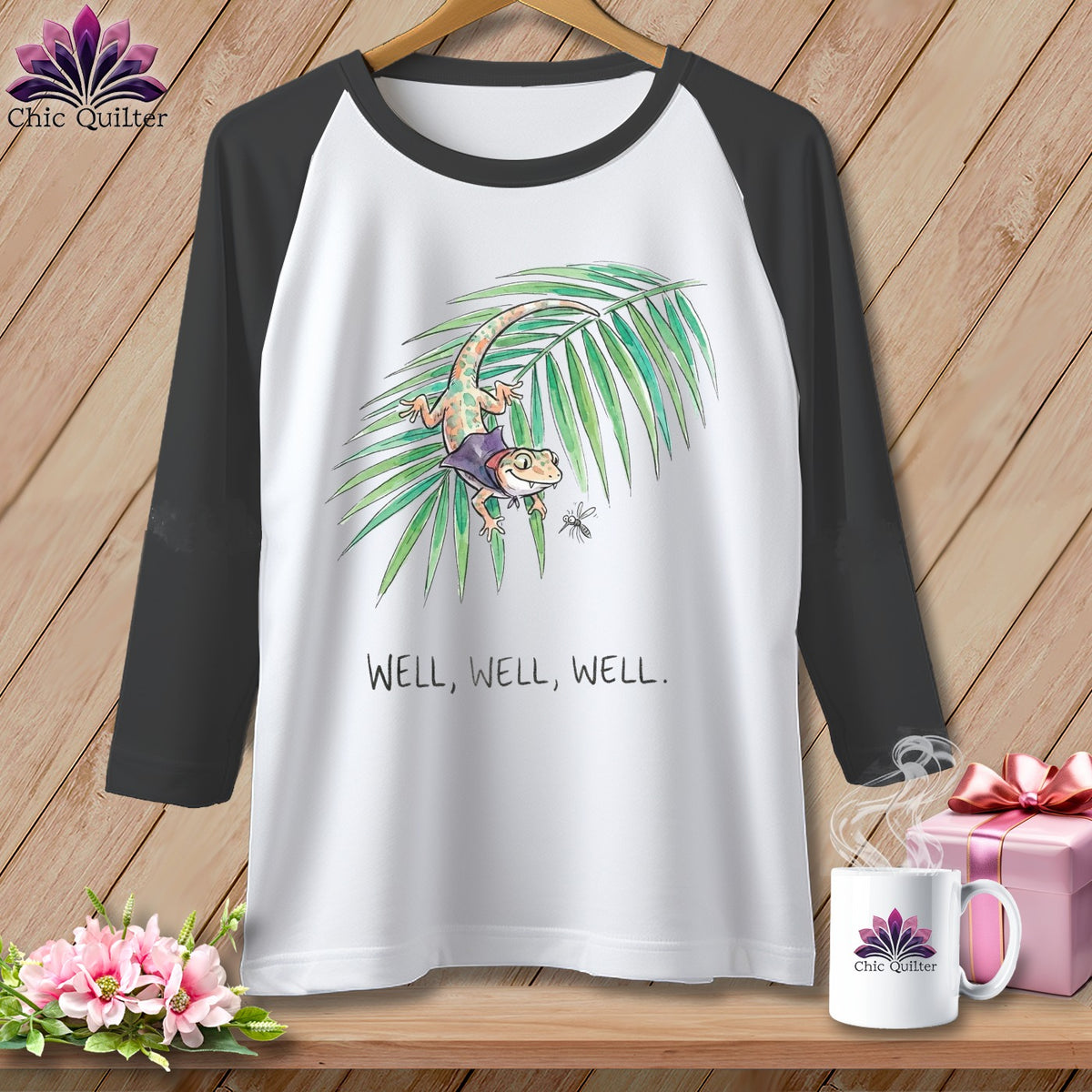 White baseball tee with a gecko on a leaf and the text "Well, Well, Well."