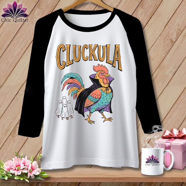 Raglan t-shirt with a colorful rooster in a cape and ghosts, text reads "CLUCKULA".