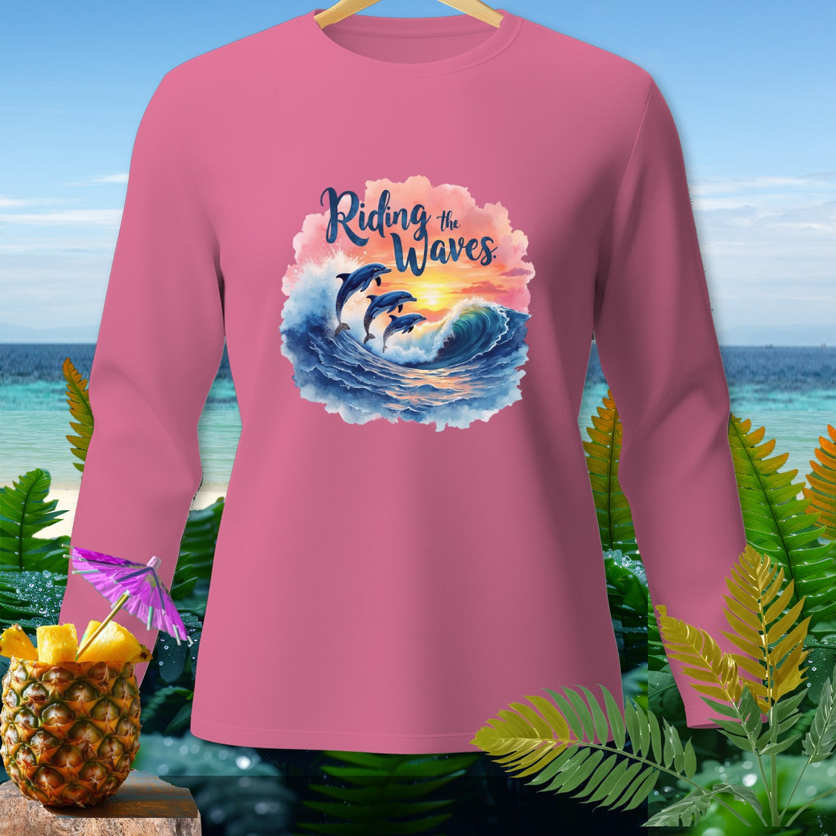 Pink long-sleeve shirt with dolphins riding waves and the text "Riding the Waves."