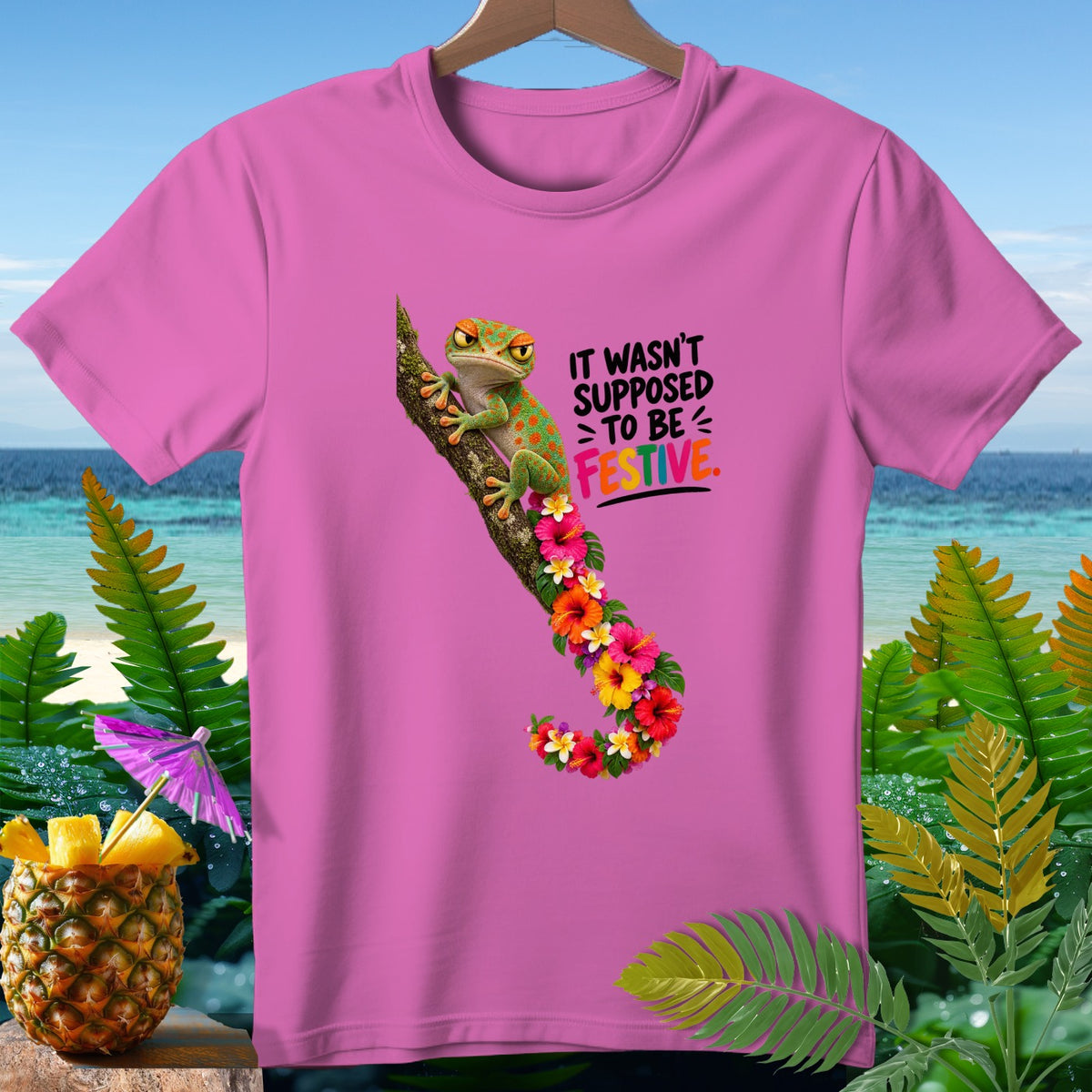 Pink t-shirt with gecko, flowers, and text "IT WASN'T SUPPOSED TO BE FESTIVE."