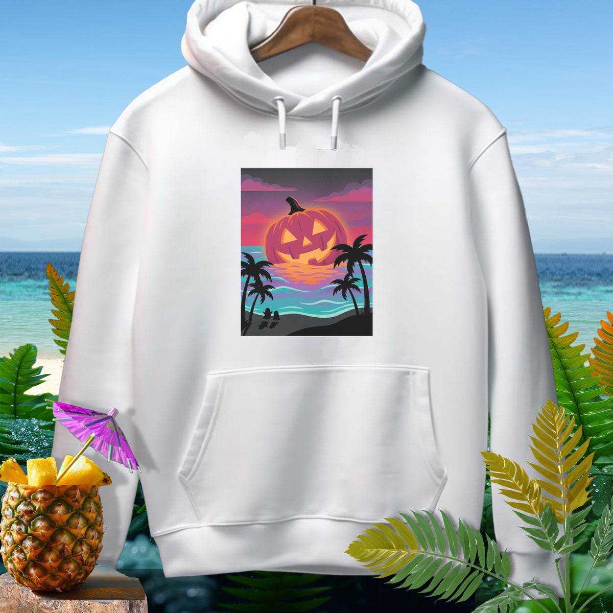 White hoodie with a graphic of a jack-o'-lantern sunset over a tropical beach.