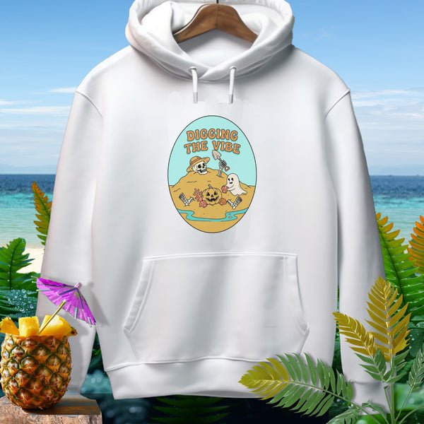 White hoodie with a graphic of skeletons and ghosts digging on a beach, text reads "DIGGING THE VIBE."