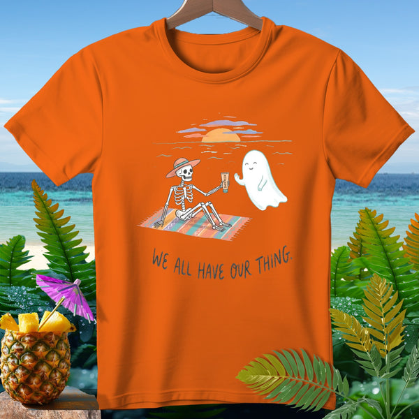 Skeleton with ghost and text "WE ALL HAVE OUR THING" on orange shirt.