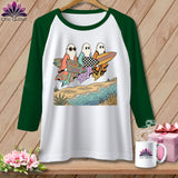 White raglan shirt with ghosts holding surfboards on a beach with 