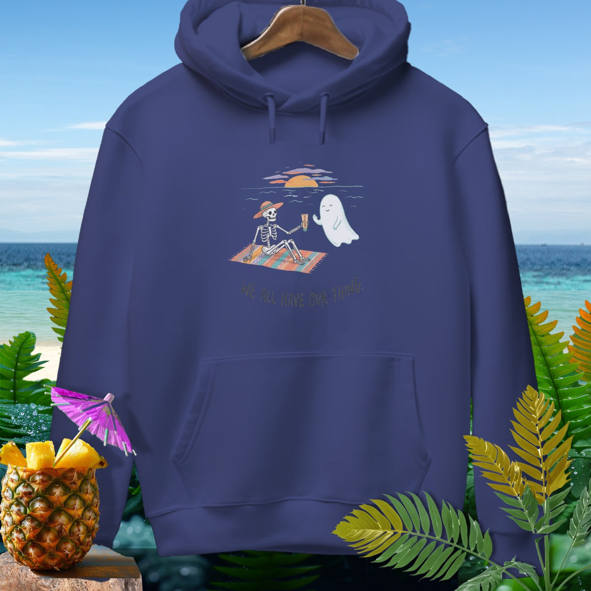 Skeleton and ghost enjoy drinks on beach blanket with text "We All Have Our Thngs."