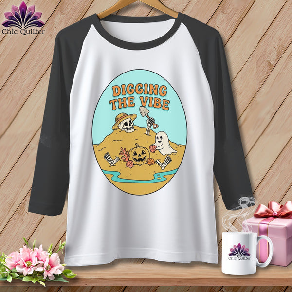 Raglan t-shirt with Halloween graphic featuring skeleton, ghost, pumpkin, and text "DIGGING THE VIBE".