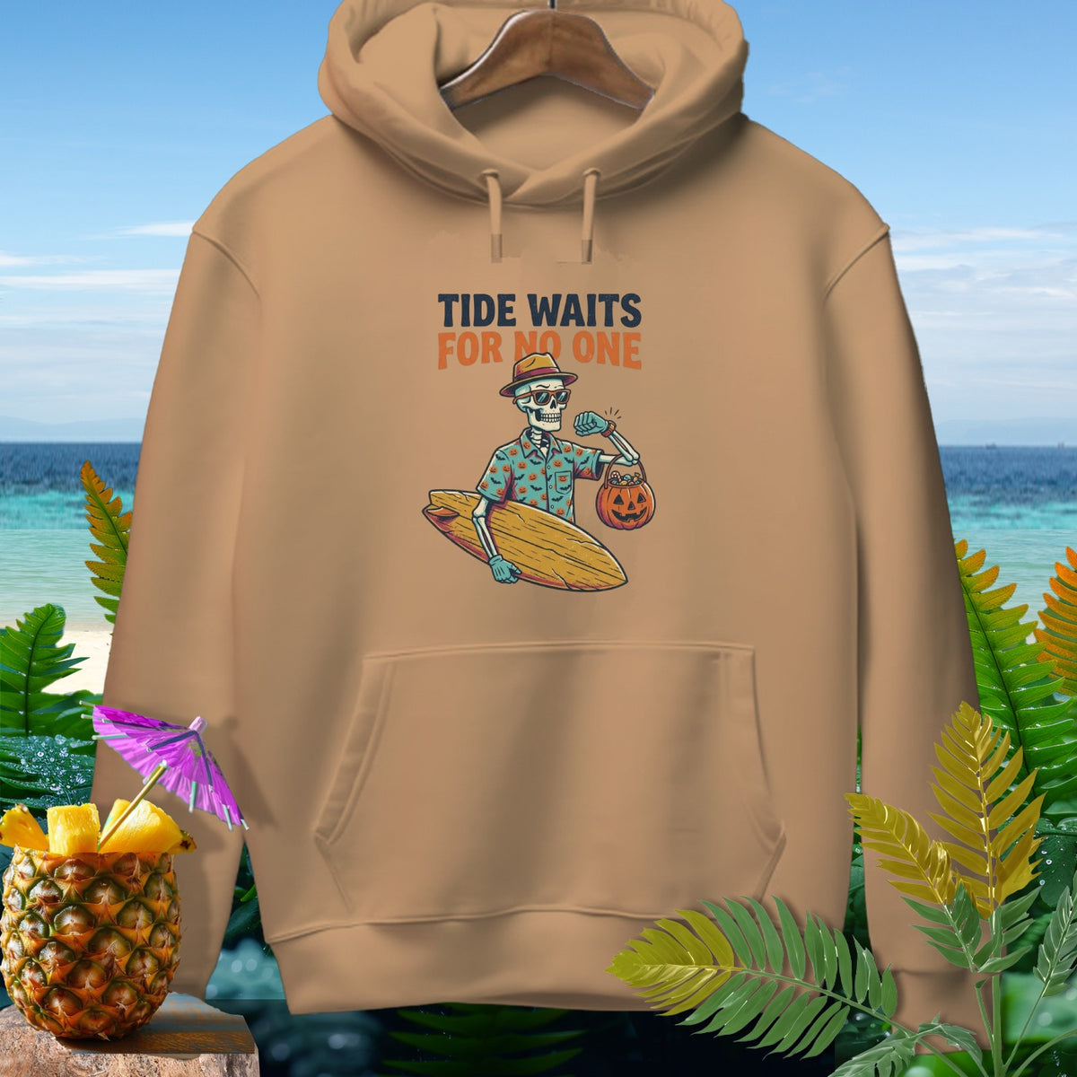 Tan hoodie featuring a skeleton in a Hawaiian shirt holding a surfboard and pumpkin bucket with text.