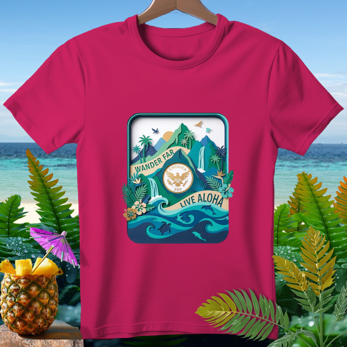 Pink t-shirt with a tropical scene design featuring mountains, waterfalls, and the text "Wander Far, America 250, Live Aloha".