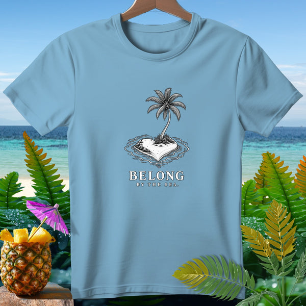 Light blue t-shirt with a heart-shaped island, palm tree, and text "BELONG BY THE SEA."