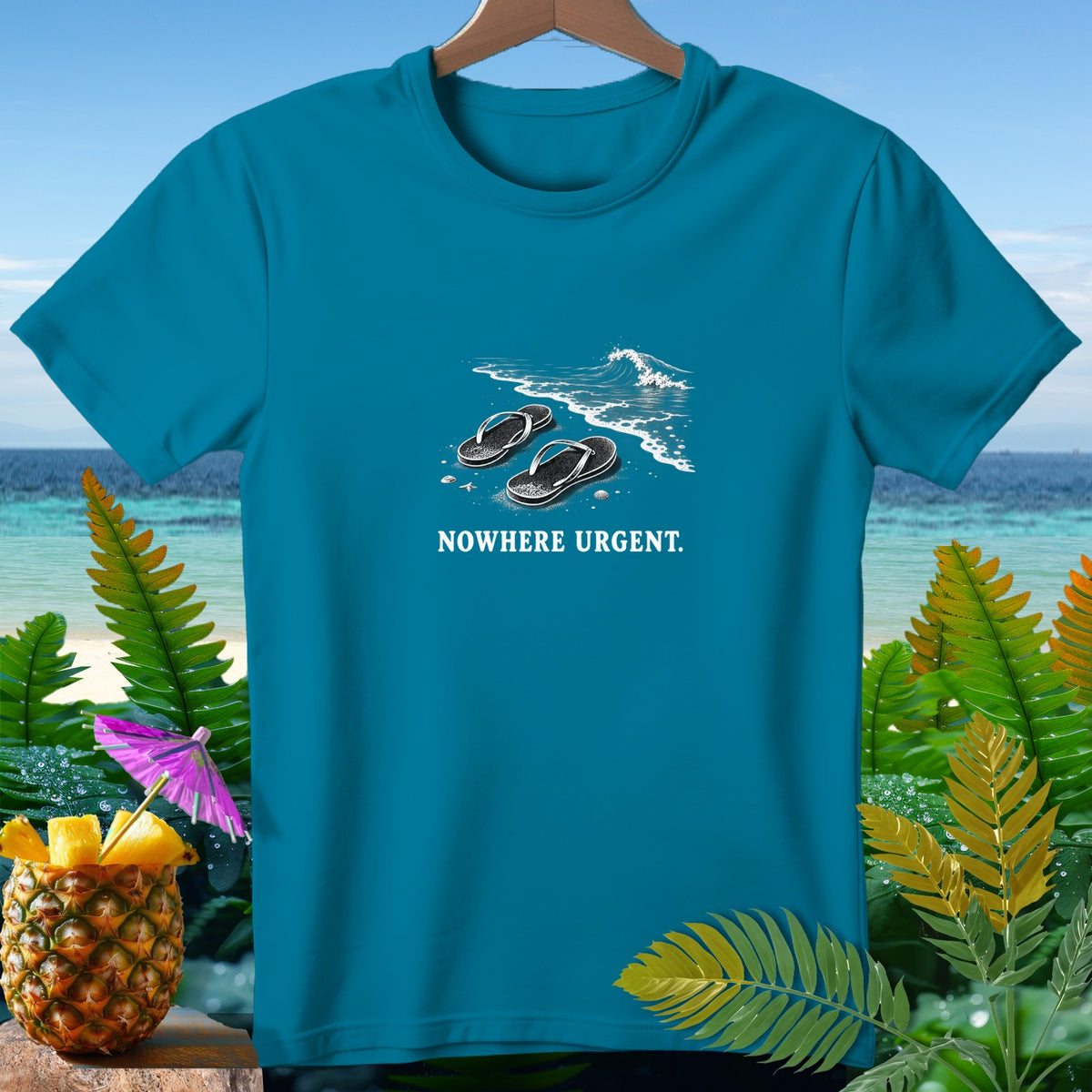 Teal t-shirt with black flip-flops on a beach and the text "NOWHERE URGENT."