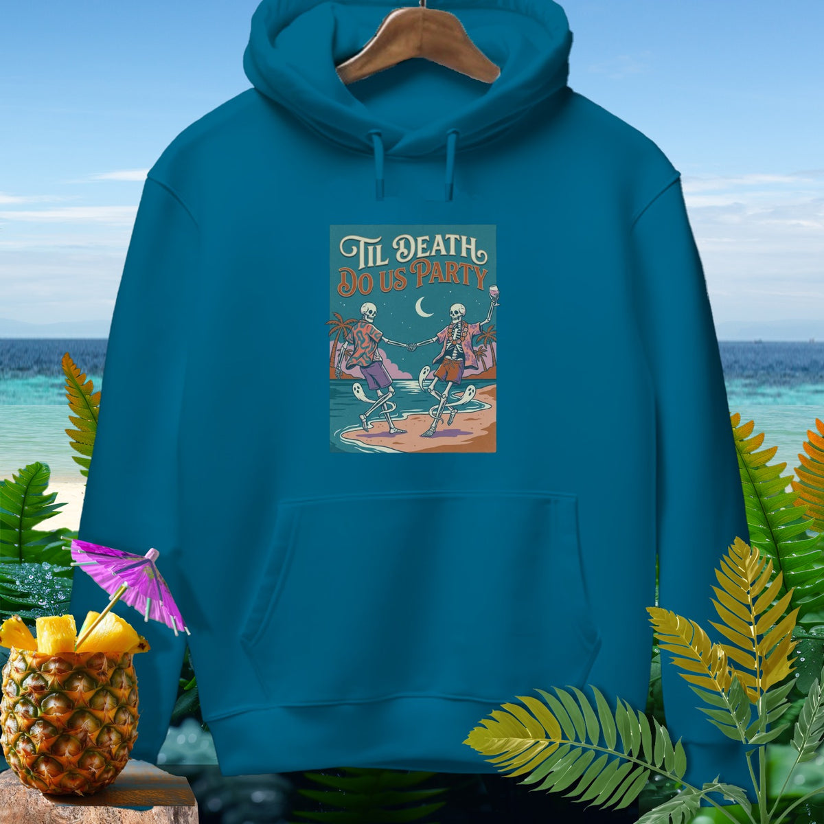 Teal hoodie with "Til Death Do Us Party" graphic of skeletons dancing on beach.