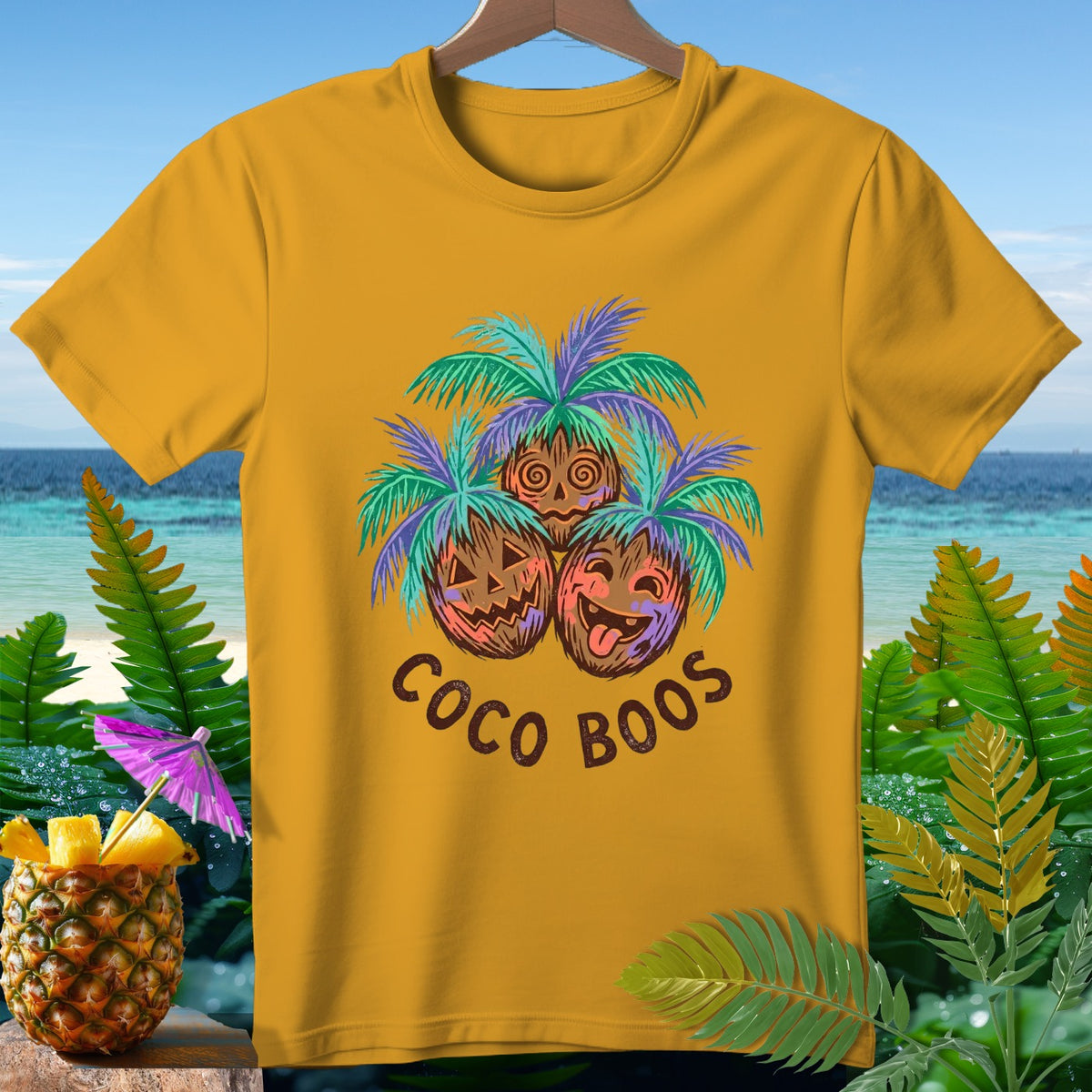 Yellow t-shirt with three coconuts dressed as pumpkins and palm trees, text "Coco Boos".