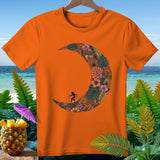 Orange t-shirt with a crescent moon graphic filled with tropical leaves and flowers, featuring a surfer.