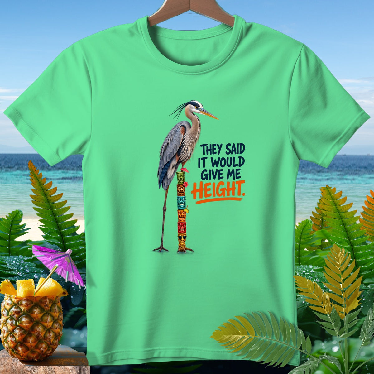 Green t-shirt with a heron standing on a totem pole, text reads "They Said It Would Give Me Height."