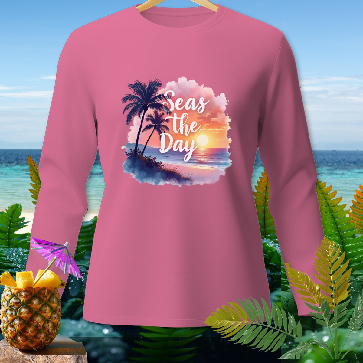 Pink long-sleeved shirt with "Seas the Day" text and beach sunset graphic.