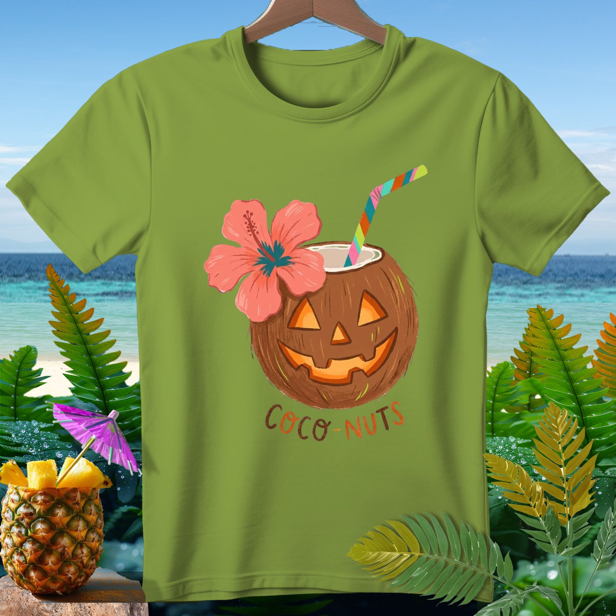 Green t-shirt with carved coconut jack-o'-lantern, hibiscus flower, straw, and "Coco-Nuts" text.