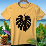 Yellow t-shirt with black monstera leaf print on beach background.