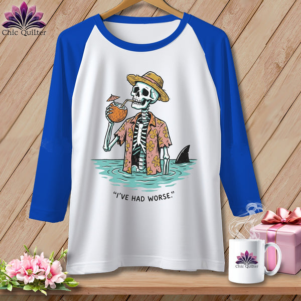 Raglan sleeve shirt with skeleton in Hawaiian shirt and hat drinking from coconut, shark fin visible.