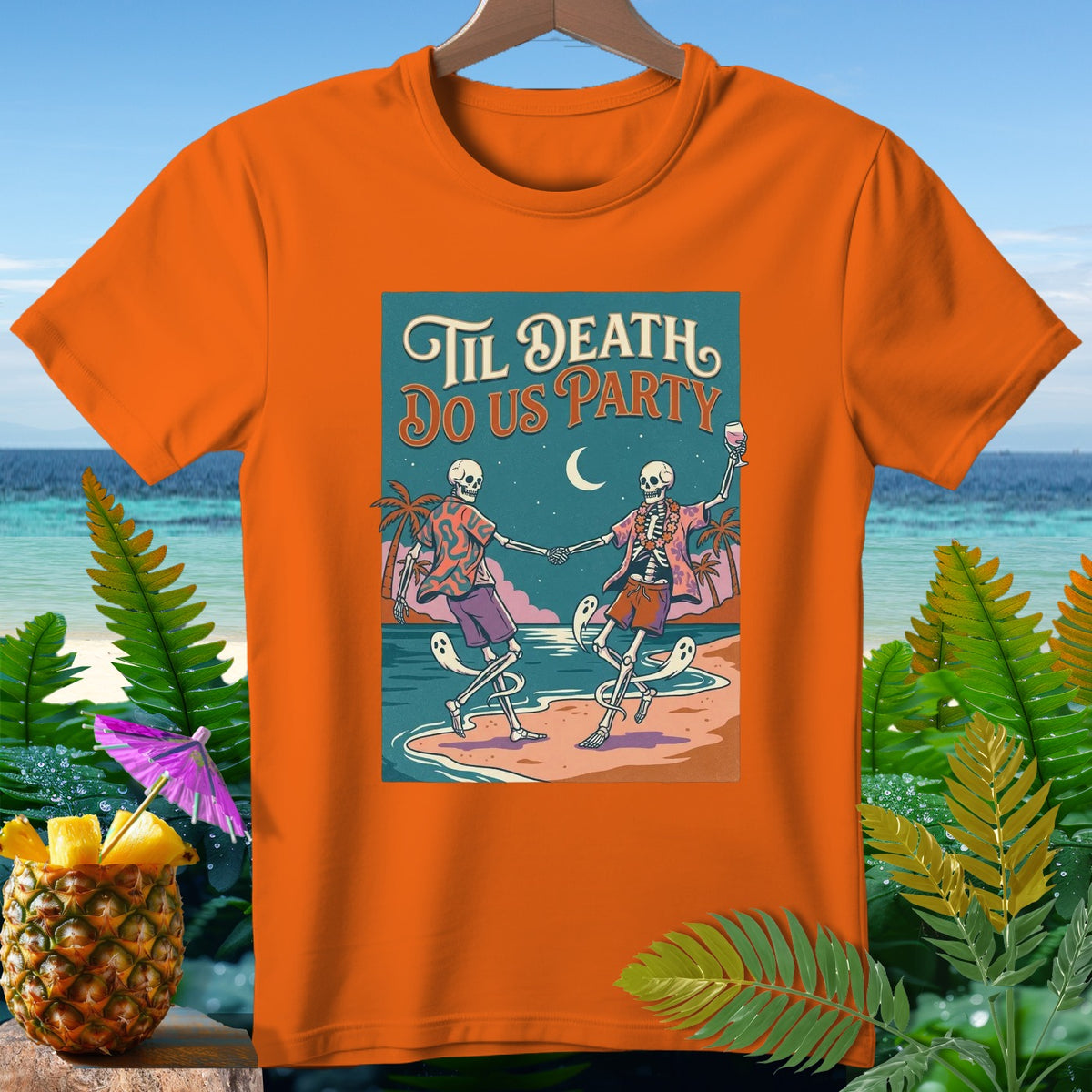 Orange t-shirt with "Til Death Do Us Party" text and dancing skeletons on a beach.