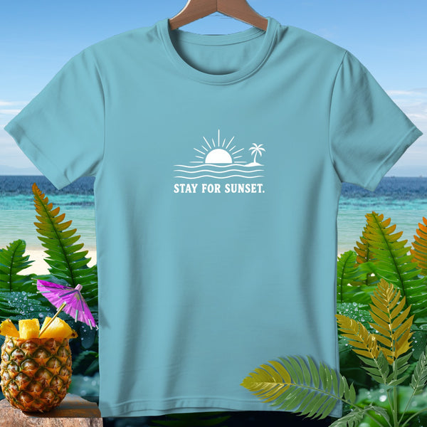 Light blue t-shirt with white graphic of sun, waves, palm tree, and "Stay for Sunset."