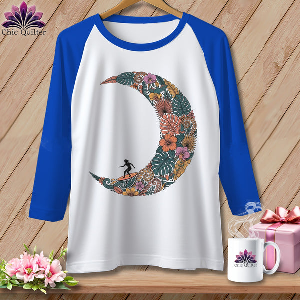 White baseball tee with a crescent moon made of tropical flowers and a surfer.
