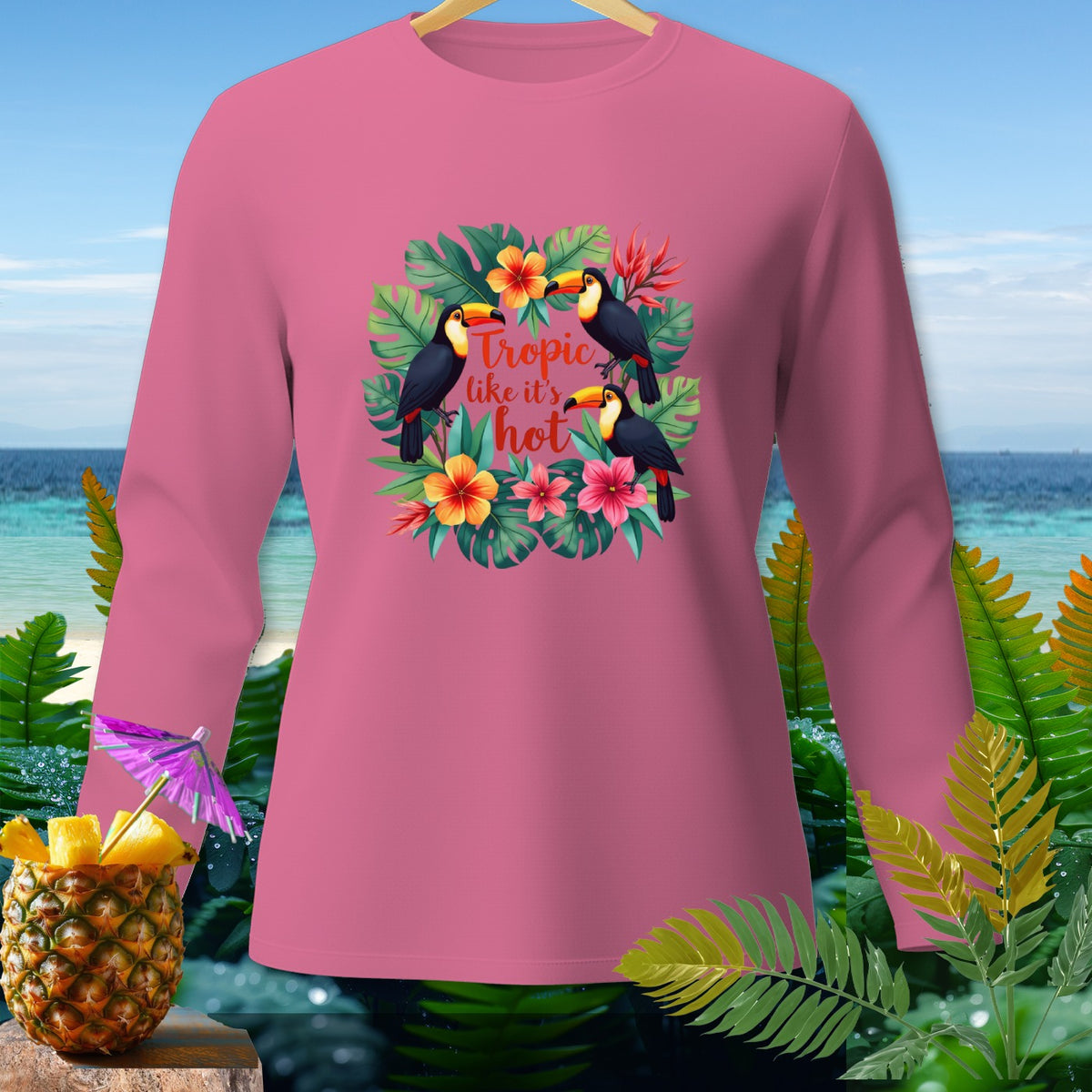 Pink long-sleeve shirt with toucans, tropical flowers, and "Tropic like it's hot" text.
