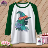 Raglan sleeve t-shirt with witch hat graphic featuring tropical leaves and flowers.