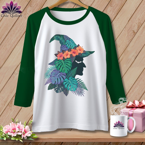 Raglan sleeve t-shirt with witch hat graphic featuring tropical leaves and flowers.
