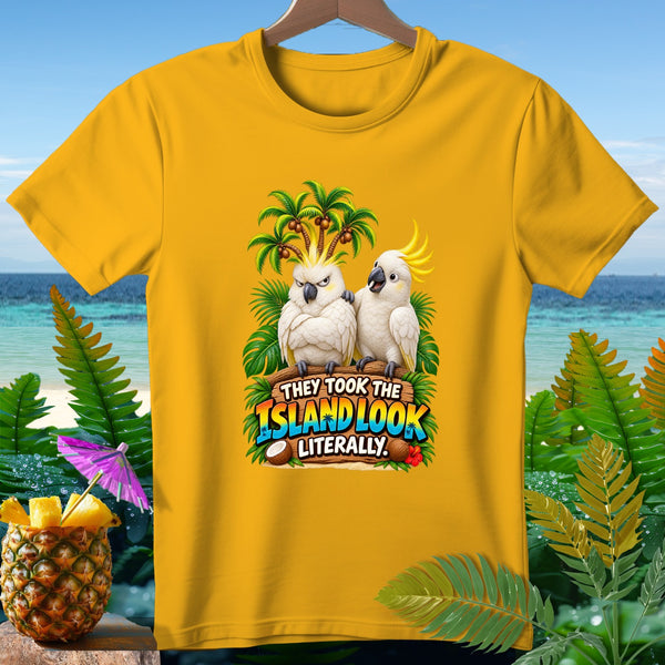 Yellow t-shirt with two cockatoos, palm trees, and text "THEY TOOK THE ISLAND LOOK LITERALLY."