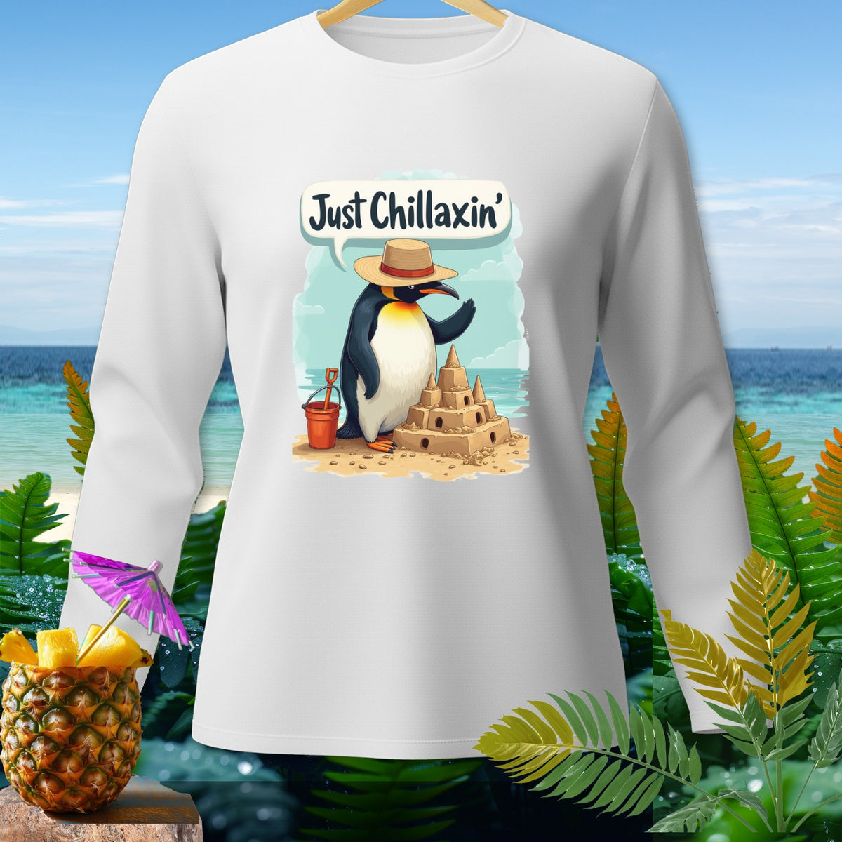 Penguin building sandcastle with text "Just Chillaxin'" on white long-sleeve shirt.